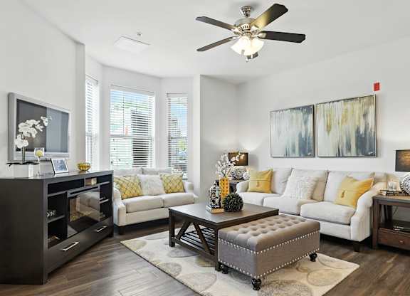A living room with a white couch, a coffee table, and a ceiling fan at Bramblett Hills Luxury Apartments in O Fallon MO 63366