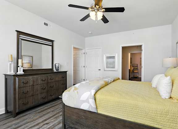 A bedroom with a bed, dresser, and mirror at Bramblett Hills Luxury Apartments in O Fallon MO 63366