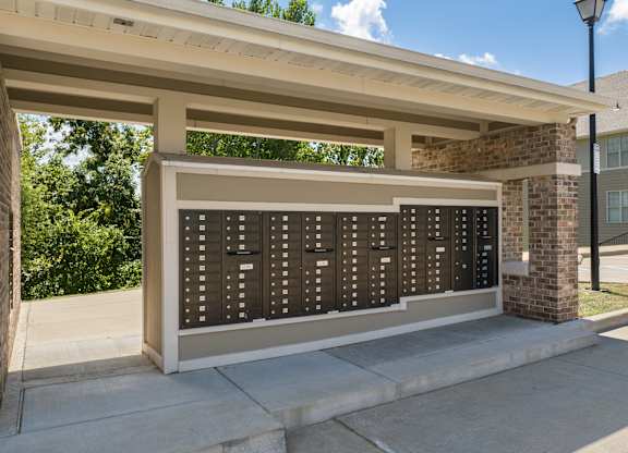 A row of mailboxes are on the sidewalk under a covered area at Bramblett Hills Luxury Apartments in O Fallon MO 63366
