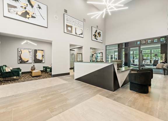 A black and white abstract painting hangs on a white wall in a modern office lobby.