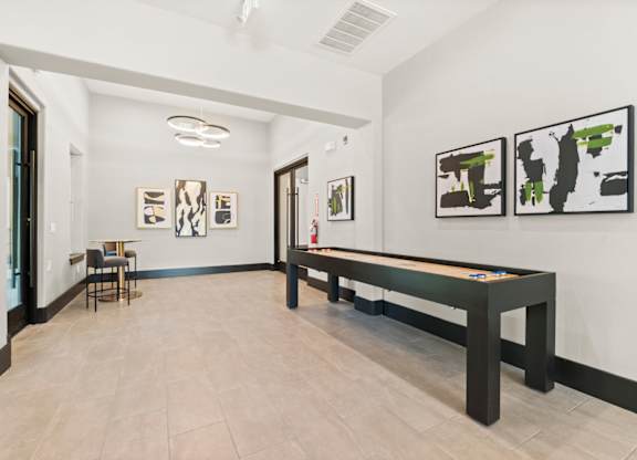 A room with a pool table and paintings on the wall.