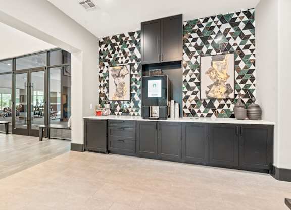 A kitchen with black cabinets and a tiled wall.