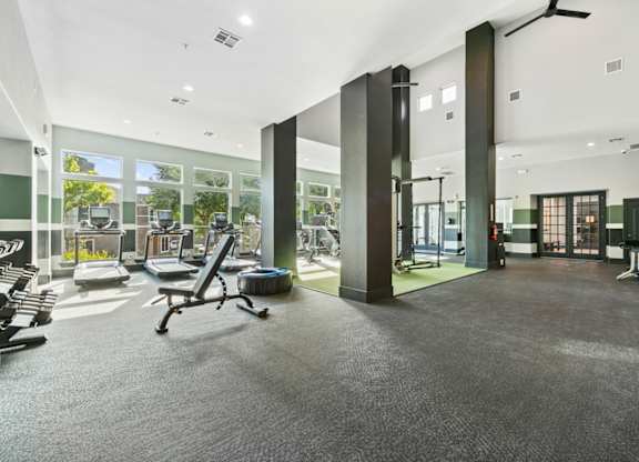 A gym with a variety of equipment including treadmills, weights, and exercise machines.