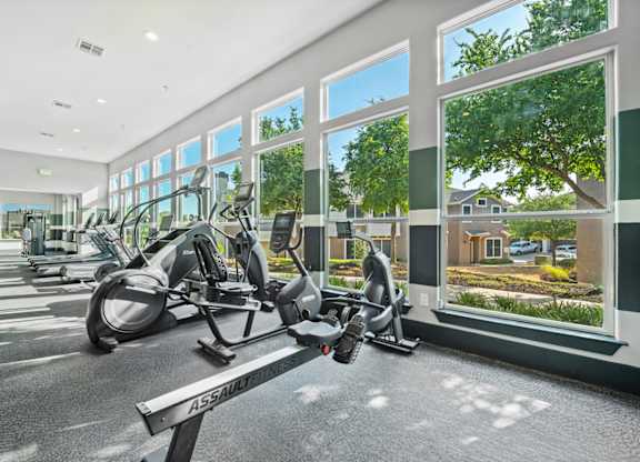A gym with a row of exercise bikes and a bench with the word
