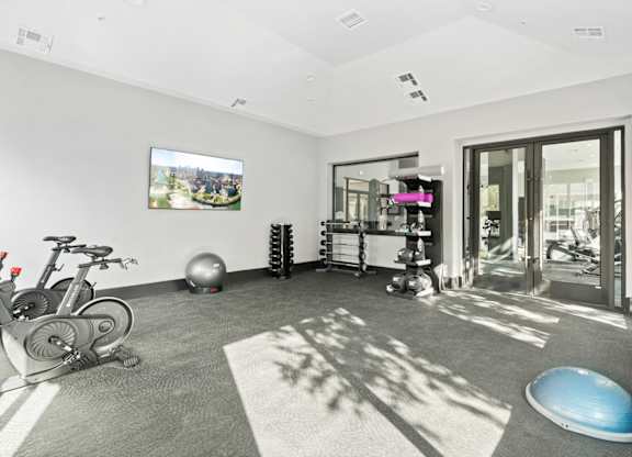 A room with a bicycle, exercise equipment, and a television.