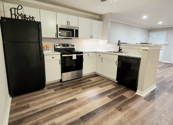 a kitchen with white cabinets and black appliances and a ceiling fan
