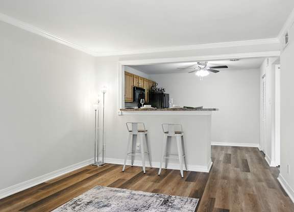 A kitchen with white walls and wooden floors with a bar area.