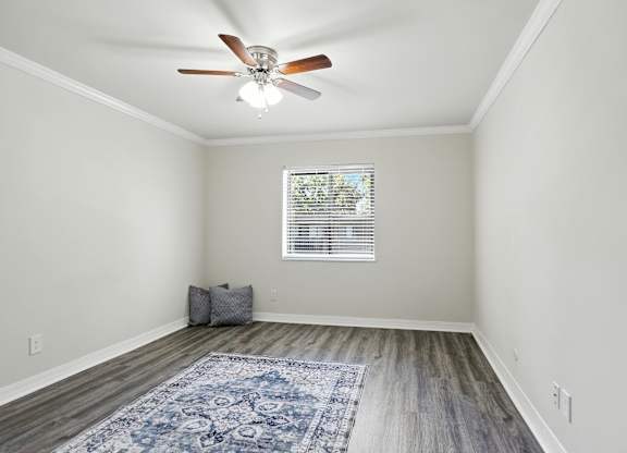 A room with a ceiling fan and a rug on the floor.