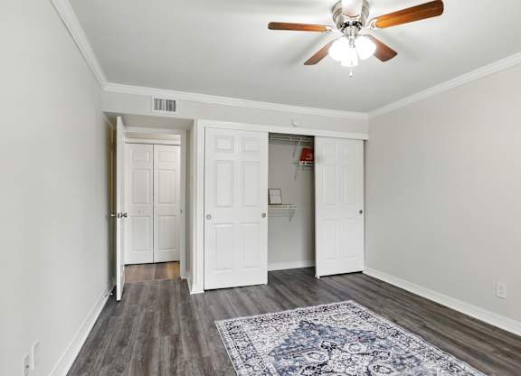 A room with a ceiling fan and a rug on the floor.