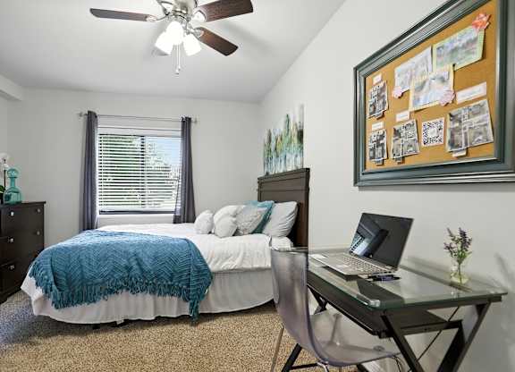 A bedroom with a bed, desk, and chair.