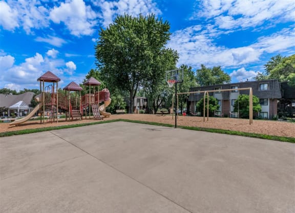 a basketball court with a playground and a building in the background