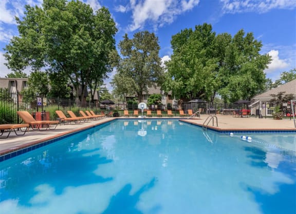 a large swimming pool with chairs around it and trees