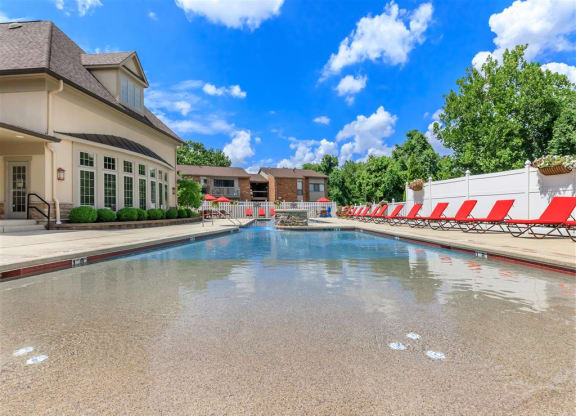 a swimming pool with a building and chairs around it