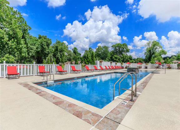 a swimming pool with red chairs around it