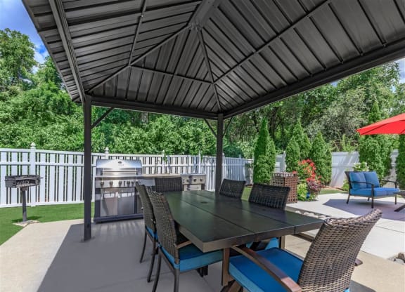 a patio with a table and chairs under a black gazebo