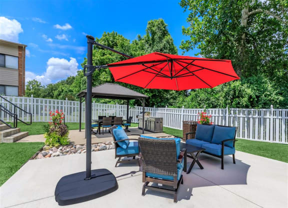 a patio with a red umbrella and a table with chairs