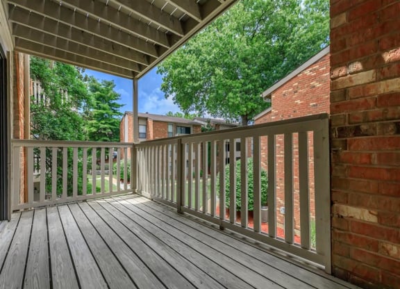 the deck of a home with a brick wall and wooden railing