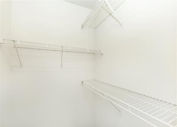 a walk in closet with white walls and shelves