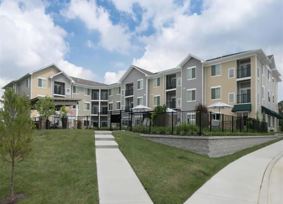 an exterior view of an apartment building with grass and a sidewalk
