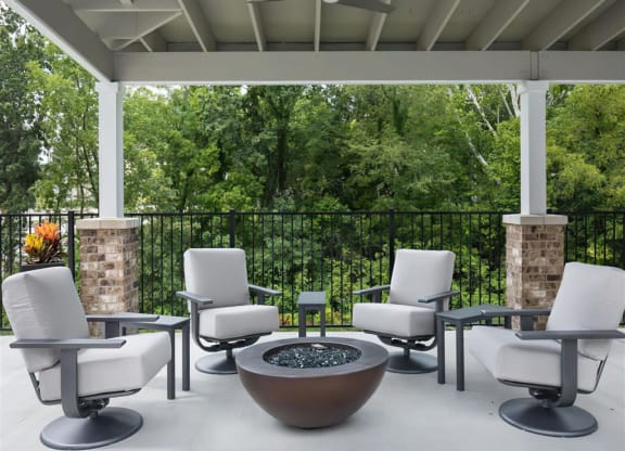 a patio with chairs and tables and a fire pit