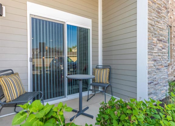 a patio with two chairs and a table on a porch
