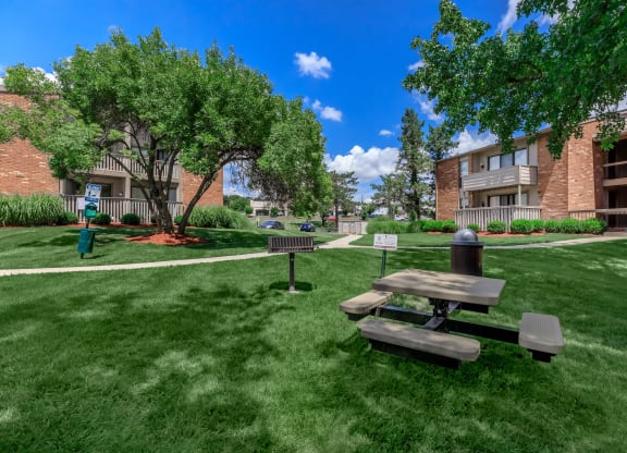 a picnic table in the grass outside of an apartment building