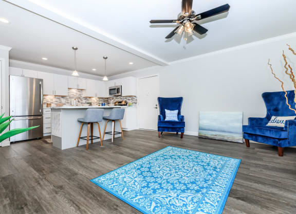 a living room with a kitchen and a ceiling fan