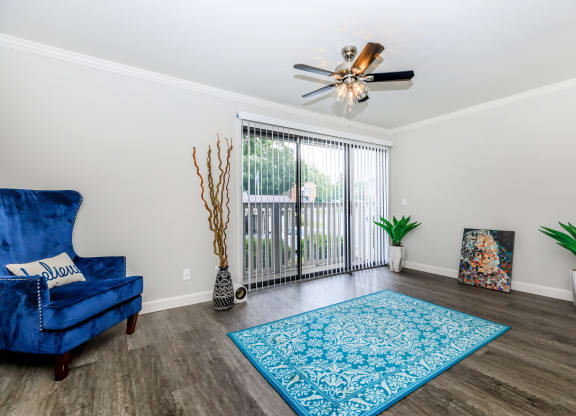 a living room with a blue chair and a ceiling fan