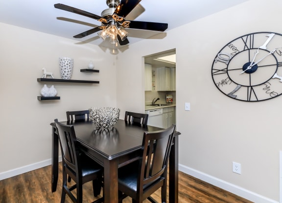 a dining room with a table and chairs and a large clock on the wall