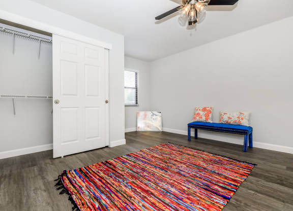 a living room with a ceiling fan and a colorful rug