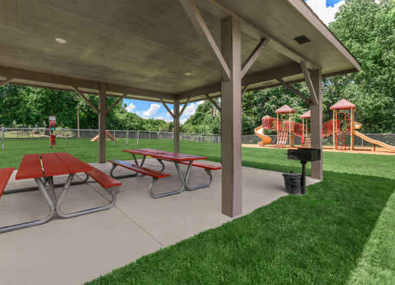 a picnic pavilion with picnic tables in front of a playground