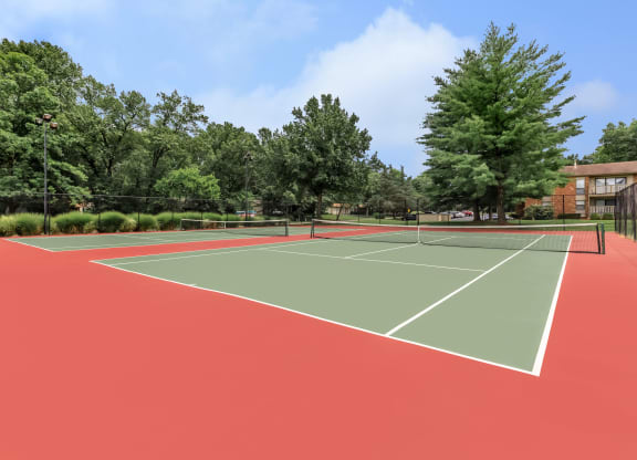 a tennis court with trees and a building in the background