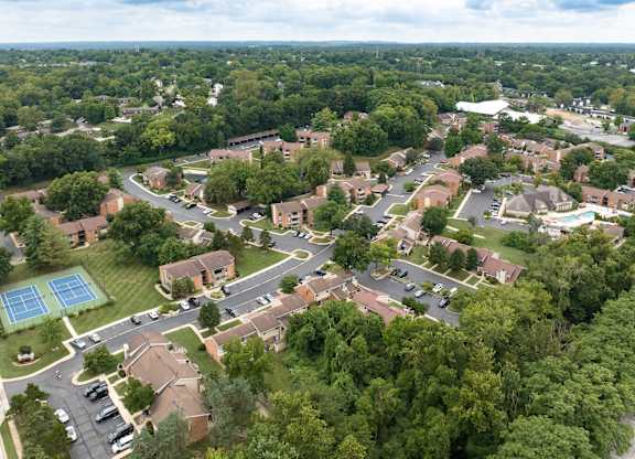 A bird's eye view of a residential area with a tennis court.