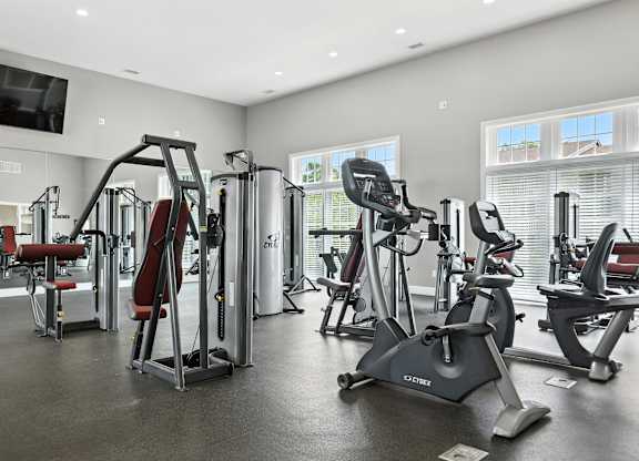 A gym with a variety of exercise equipment including treadmills, stationary bikes, and weight machines.