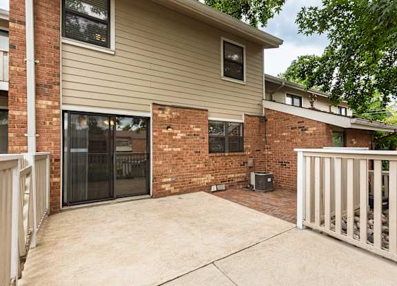 A house with a brown brick wall and a white fence.