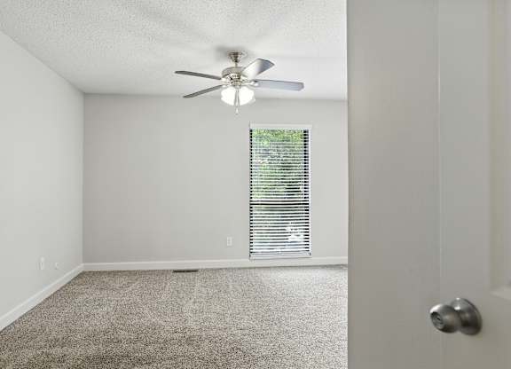 A room with a ceiling fan and carpeted floor.