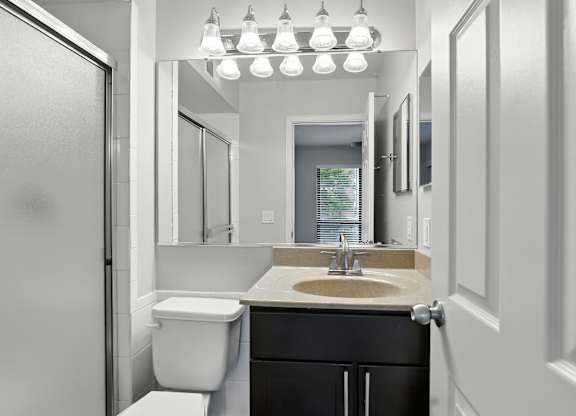 A bathroom with a toilet, sink, and mirror.