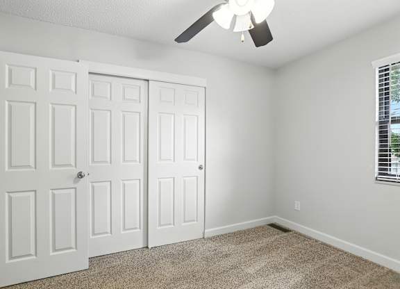 A room with a white door and a ceiling fan.