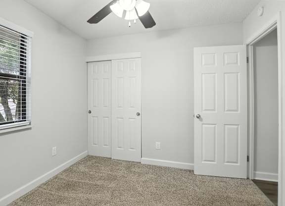 A room with a ceiling fan and two doors.