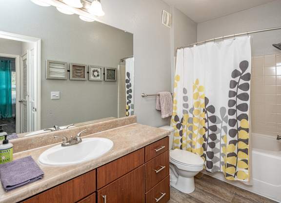 A bathroom with a white sink, a toilet, and a shower curtain with yellow and grey circles.