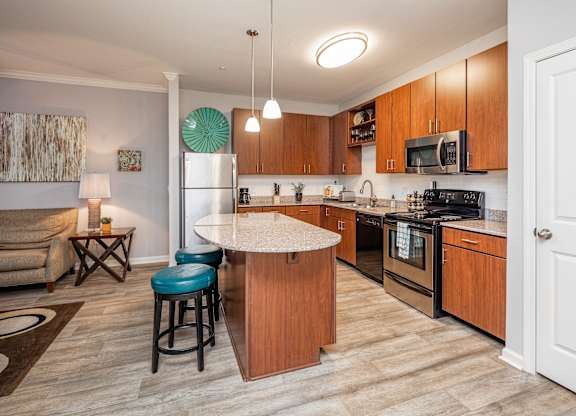 A kitchen with a white island and blue stools.
