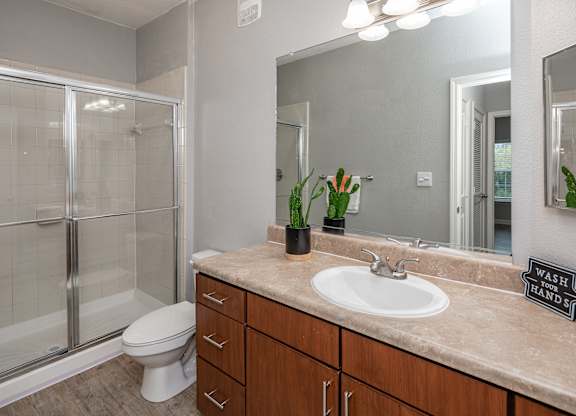 A bathroom with a toilet, sink, and mirror.