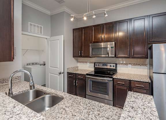 A kitchen with a granite countertop and stainless steel appliances.