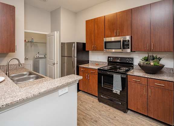 A kitchen with a black oven and wooden cabinets.