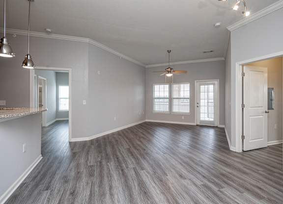 A spacious room with a ceiling fan and hardwood flooring.