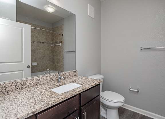 A bathroom with a granite countertop and white toilet.