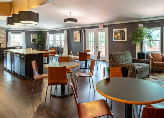 a communal area with tables and chairs and a kitchen and living room