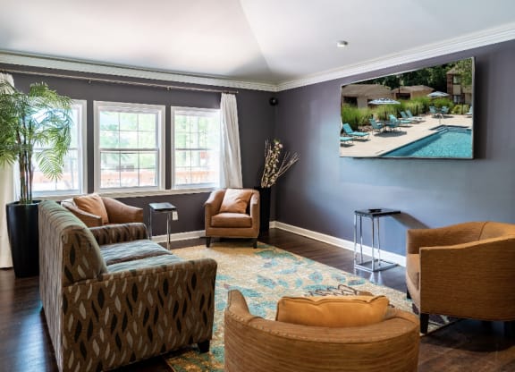 a living room with couches and chairs and a picture of a swimming pool