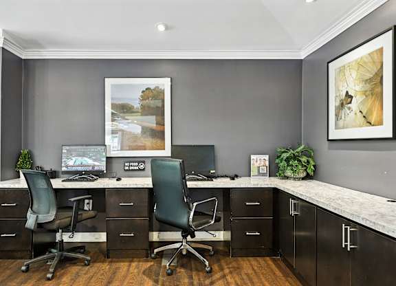 A modern home office with a desk, chairs, and a computer.