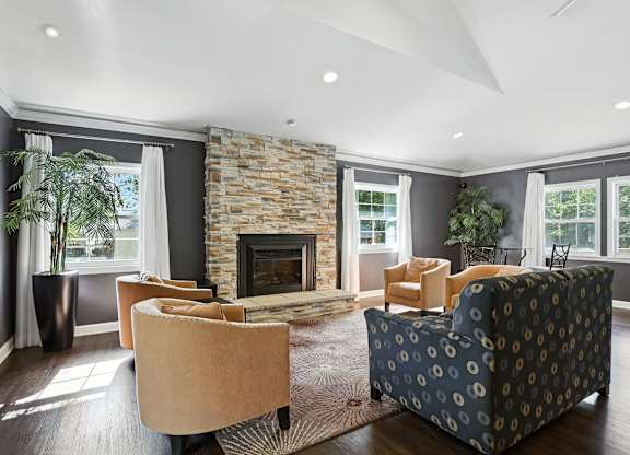 A living room with a stone fireplace and a large window.